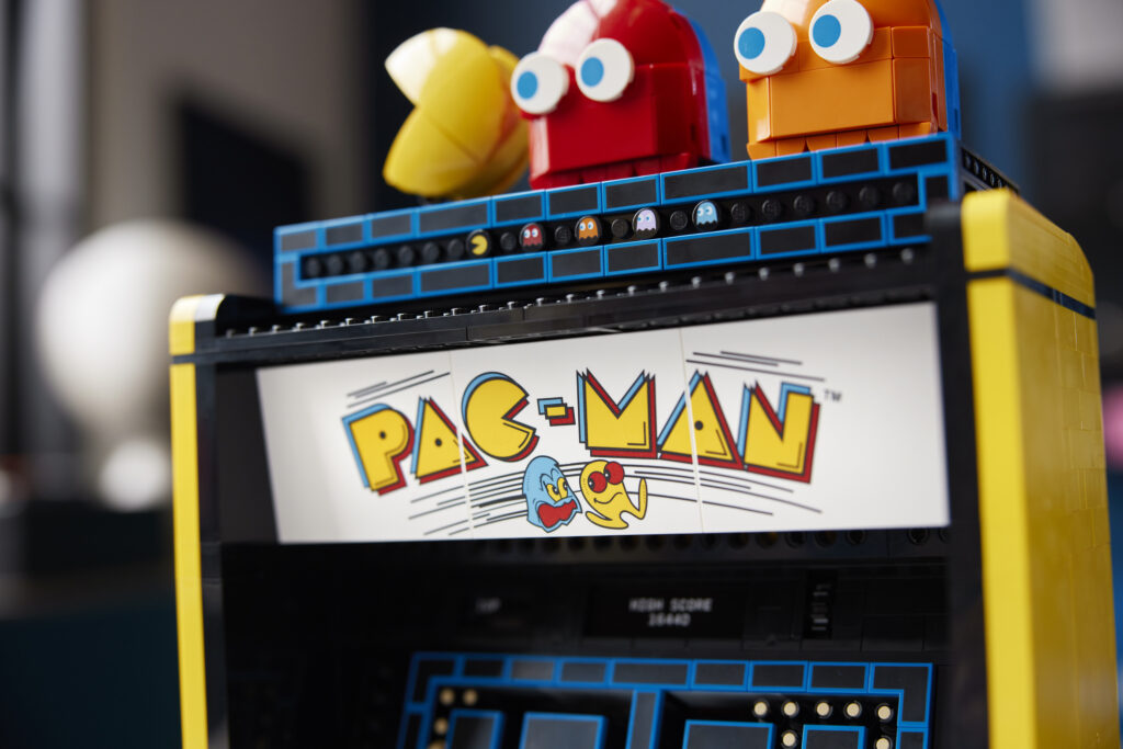 A close-up of the sign placed at the top of the LEGO cabinet and of the figures of PAC-MAN, BLINKY and CLYDE placed above it
